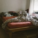 Ein Bett so bunt wie Berlin: Bettwäsche, Kissen, Decken. Und ein Stapel Bücher.